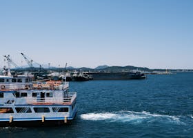 A serene coastal harbor scene featuring docked ferries and boats under a clear blue sky.